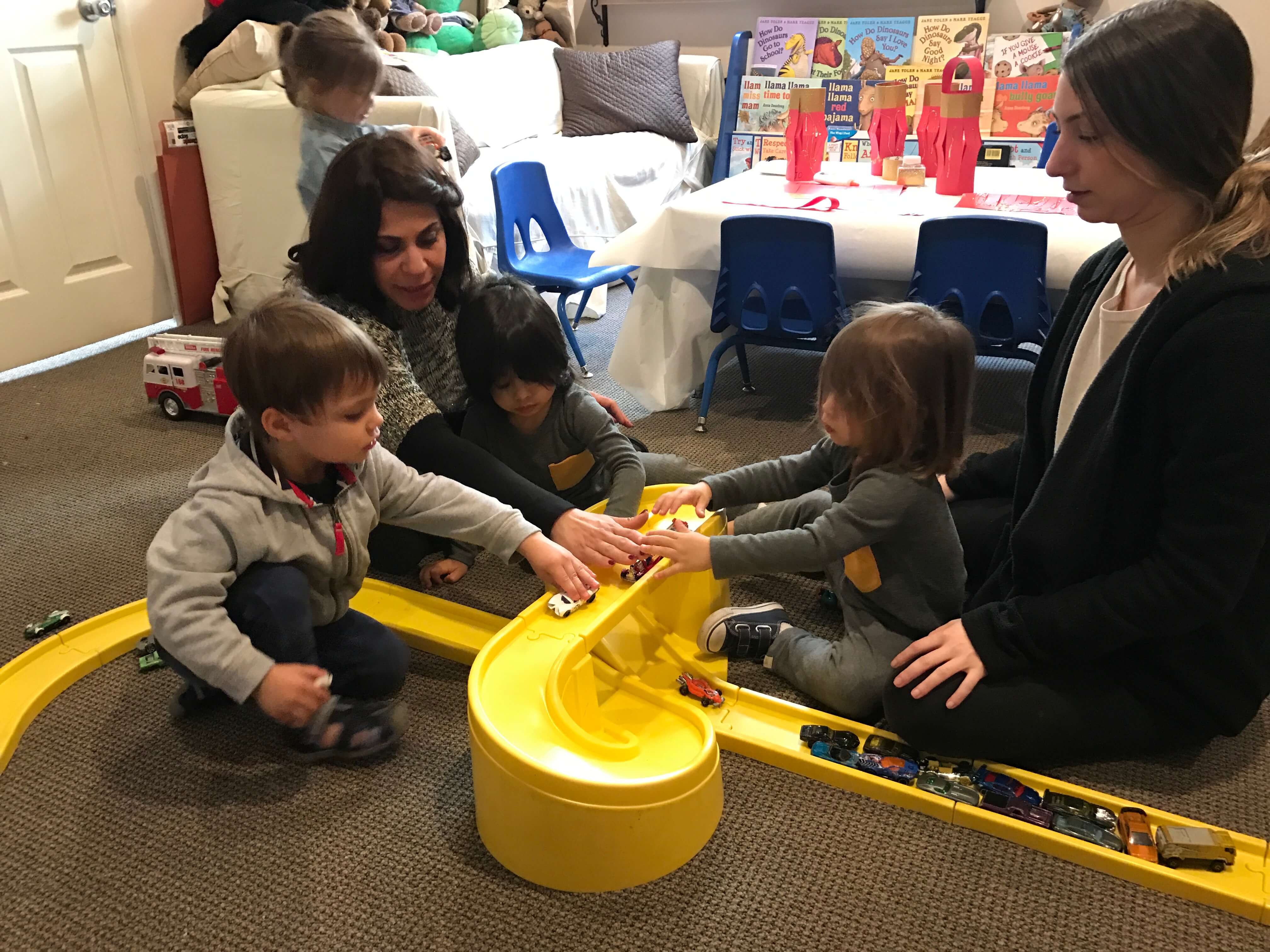 2 toddlers playing with cars on the trail, learning to take turns being supervised by adults at early childhood development class