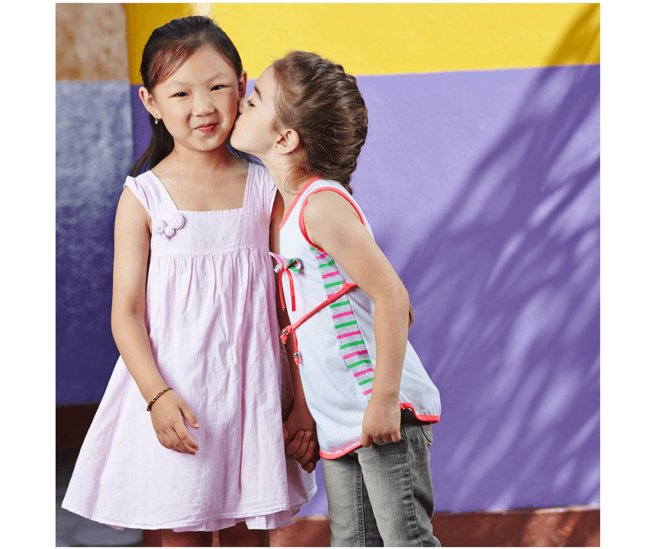 one toddler kissing another toddler on the cheek being a good friend