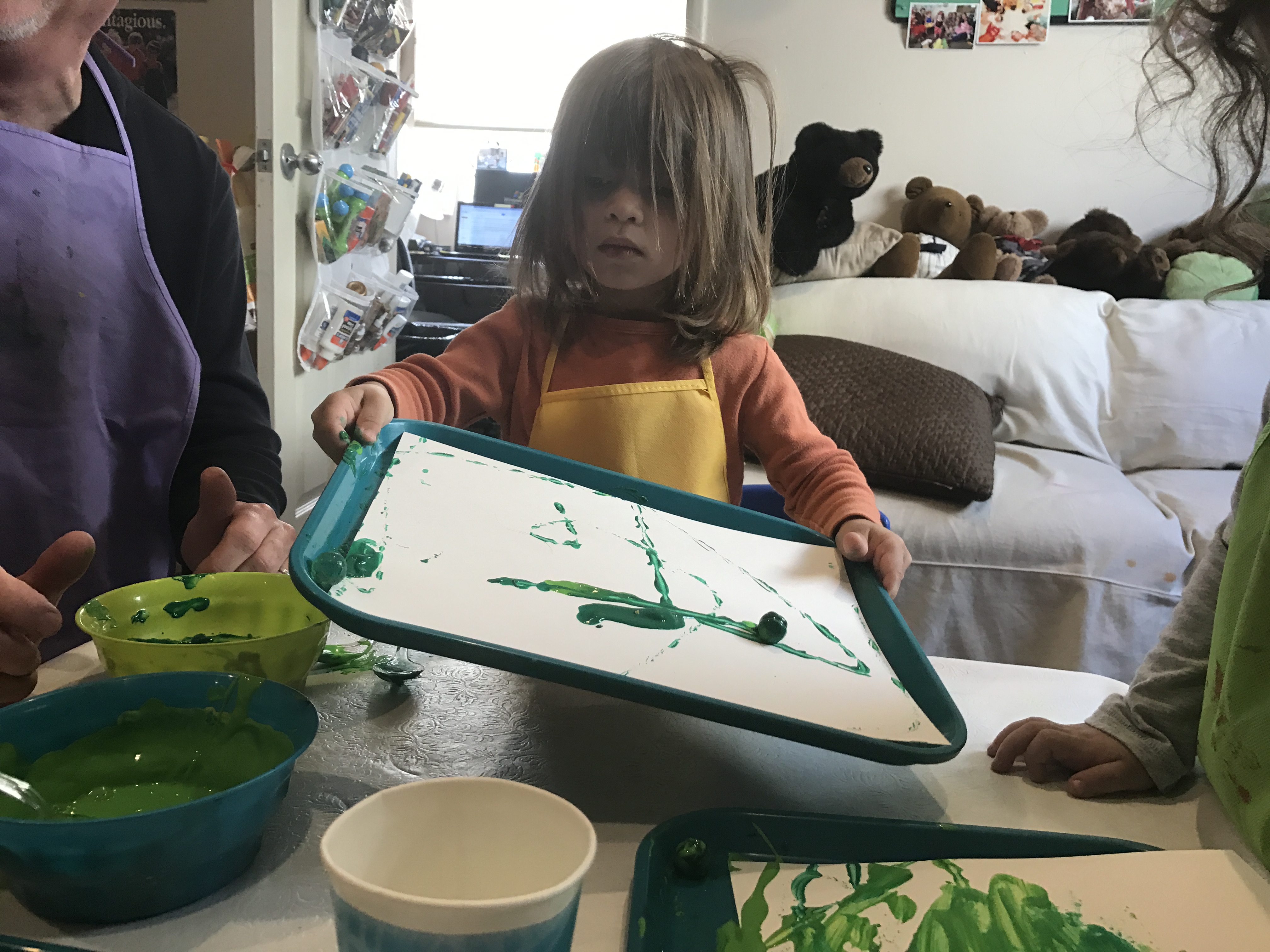 child paiting with green paint and marble at early childhood development class