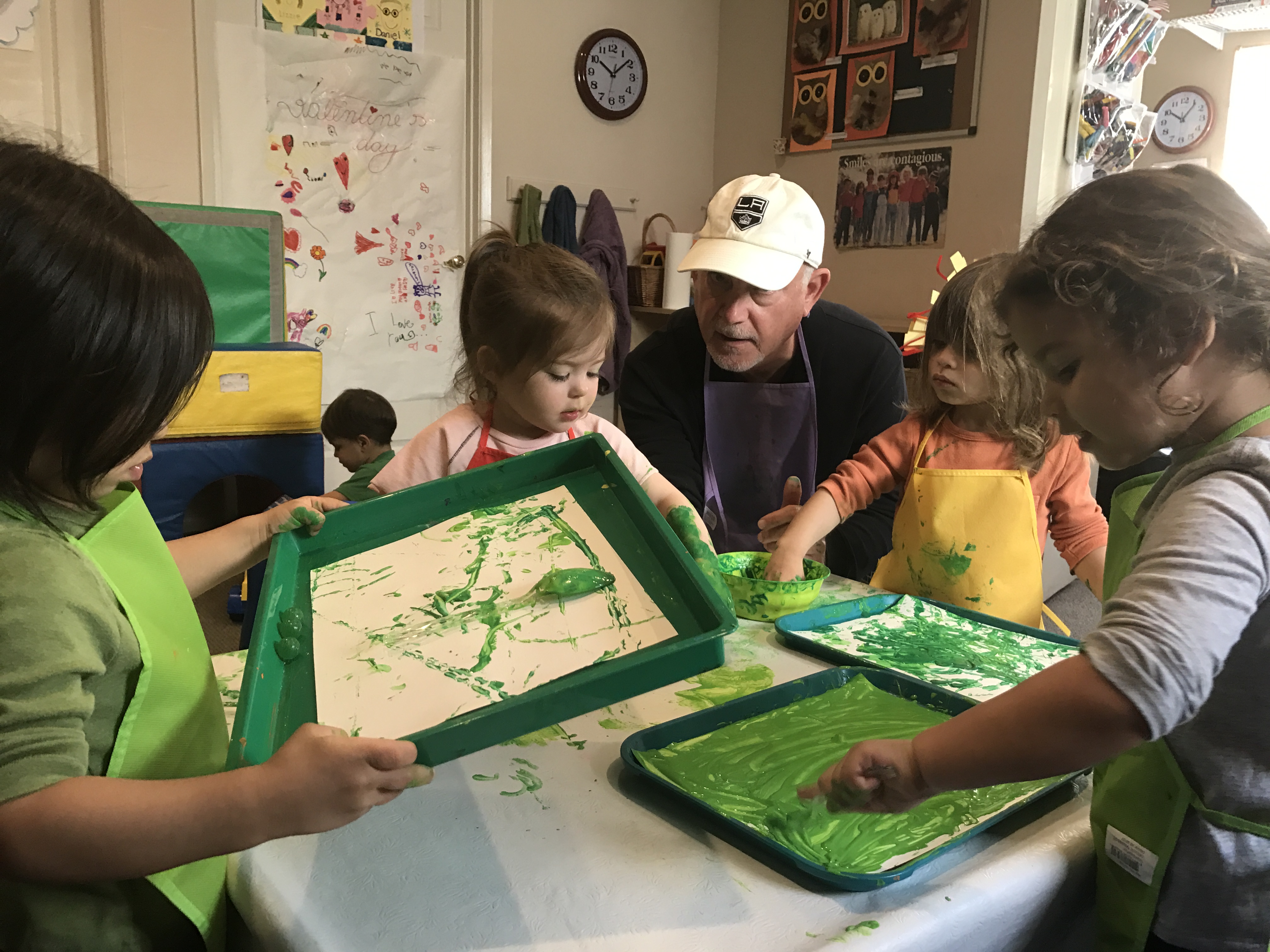 child paiting with green paint and marble at early childhood development class