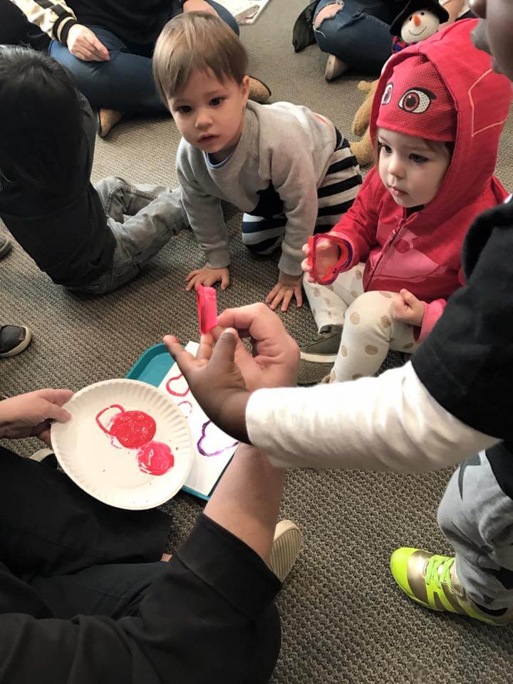 kids learning to paint hearts out of heart shaped cookie cutters at early childhood development classes