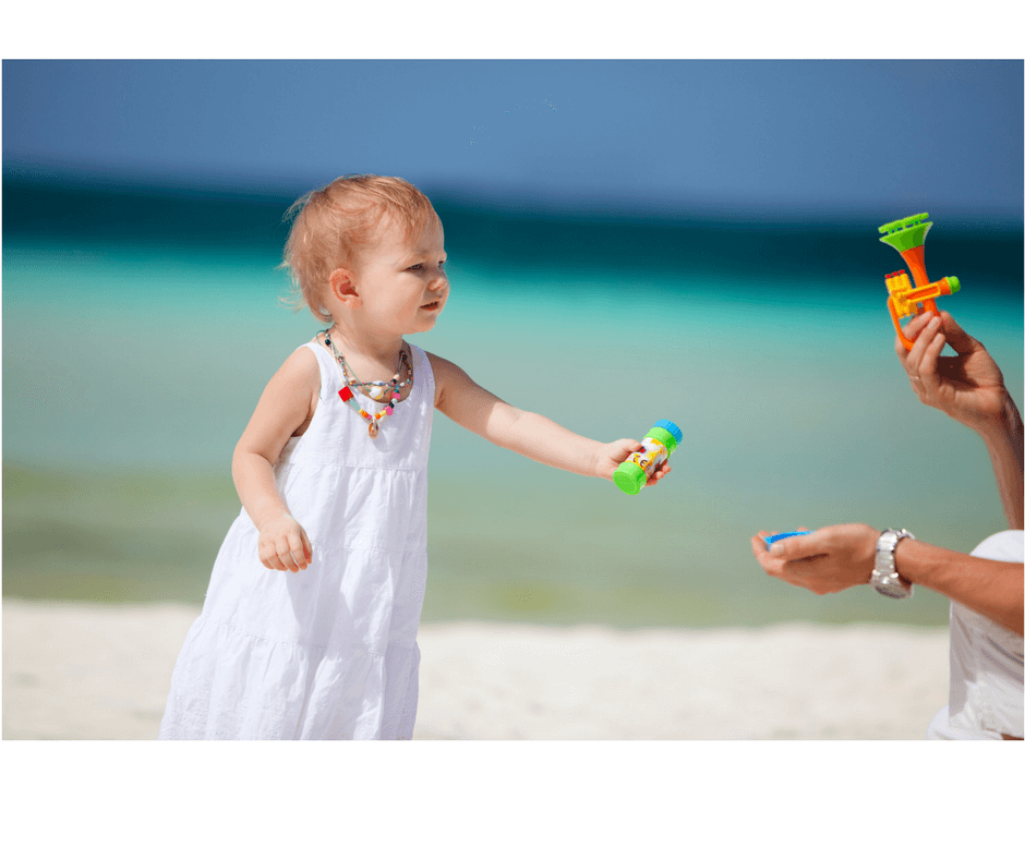 toddler at the beach chosing between toys