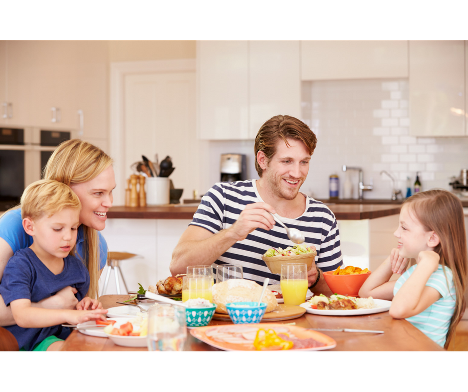 dad offering daughter food from the table while having a family meal