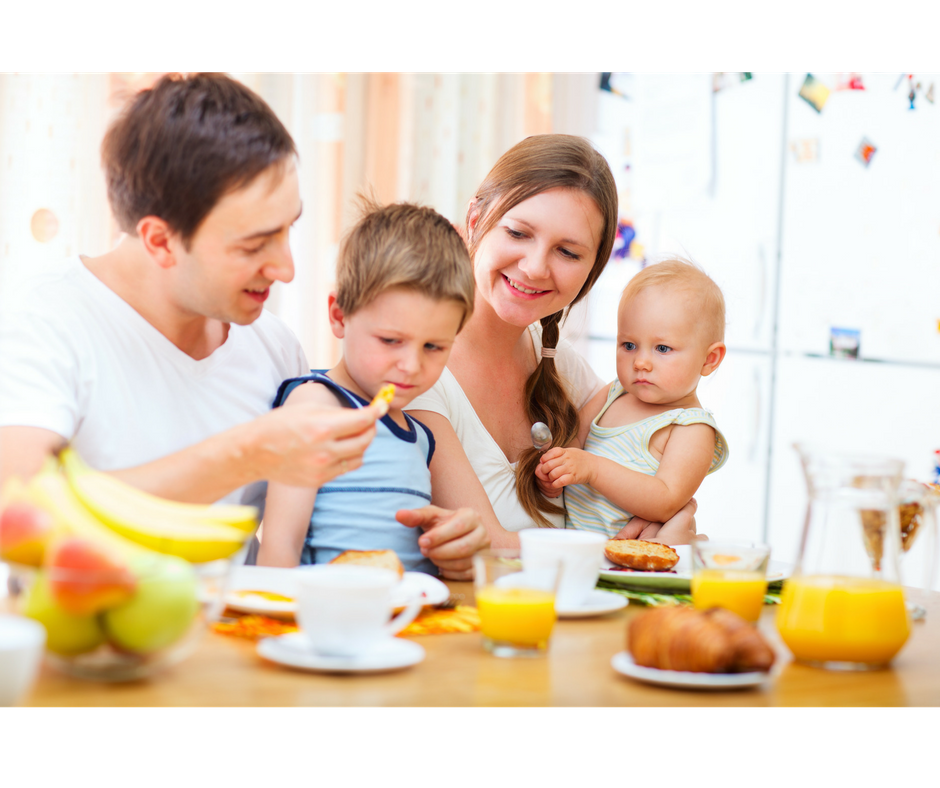 dad trying to make son taste a new food while having a family meal