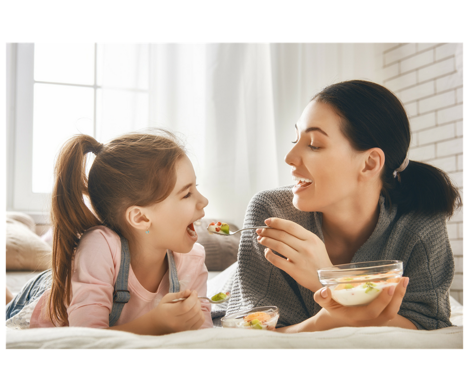 mother and daughter eating together fruits and yogurt