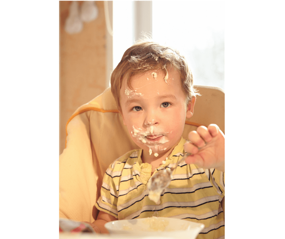 toddler making a mess while eating by himself