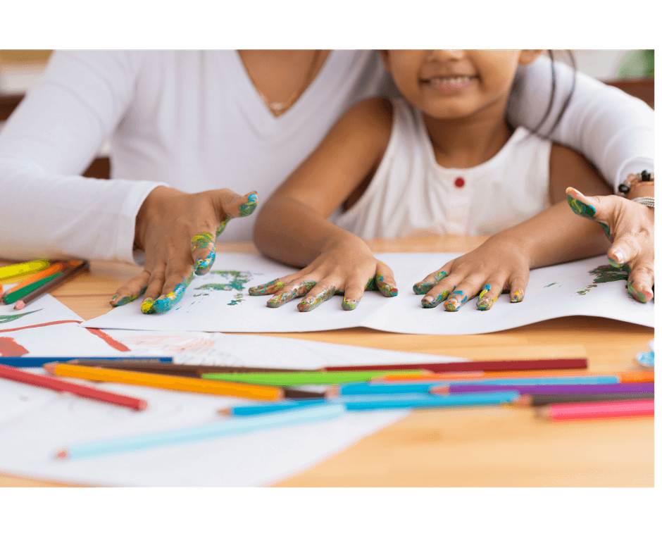 mother and daughter playing with finger paint in their hands, tracing the hands