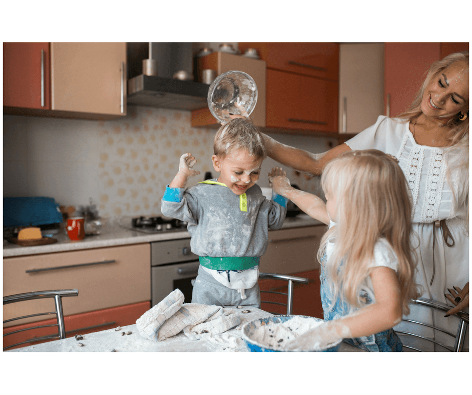 mother and 2 children messy playing in the kitchen with flour and bowls