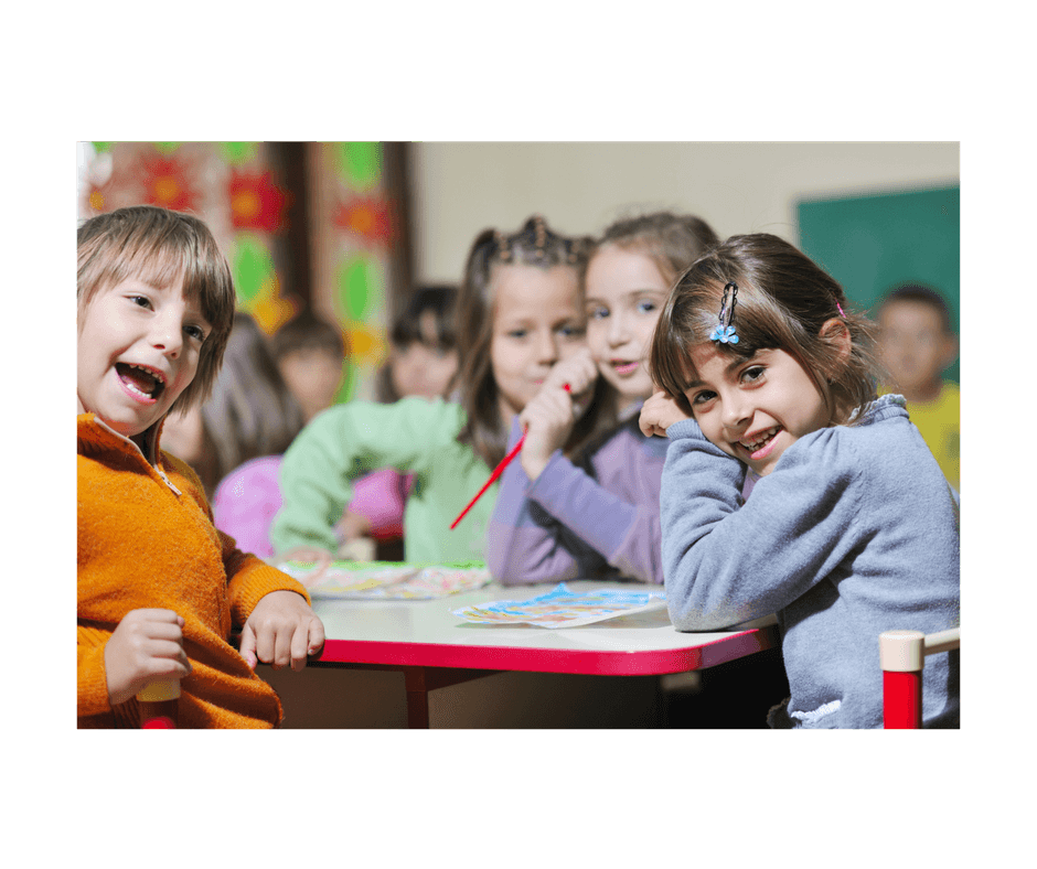 4 children at preschool class, their faces show that they might be bullying someone that is not in the picture