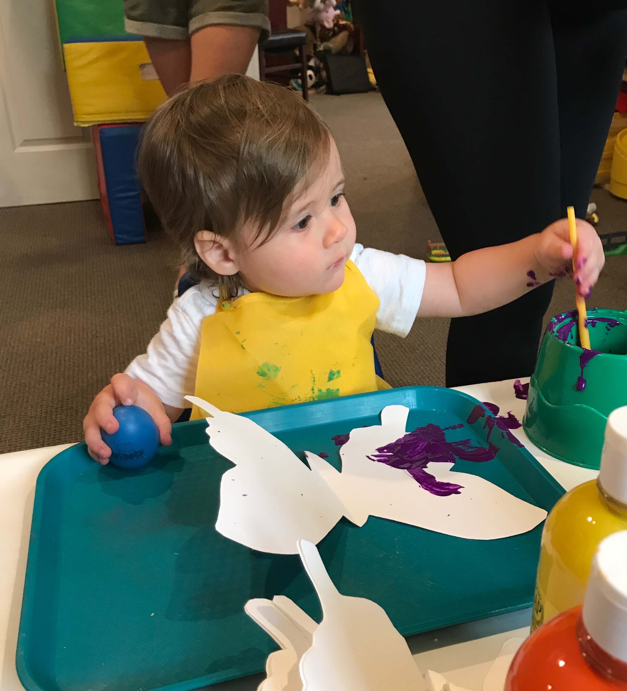 toddler painting butterfly shaped paper at early childhood development associates class