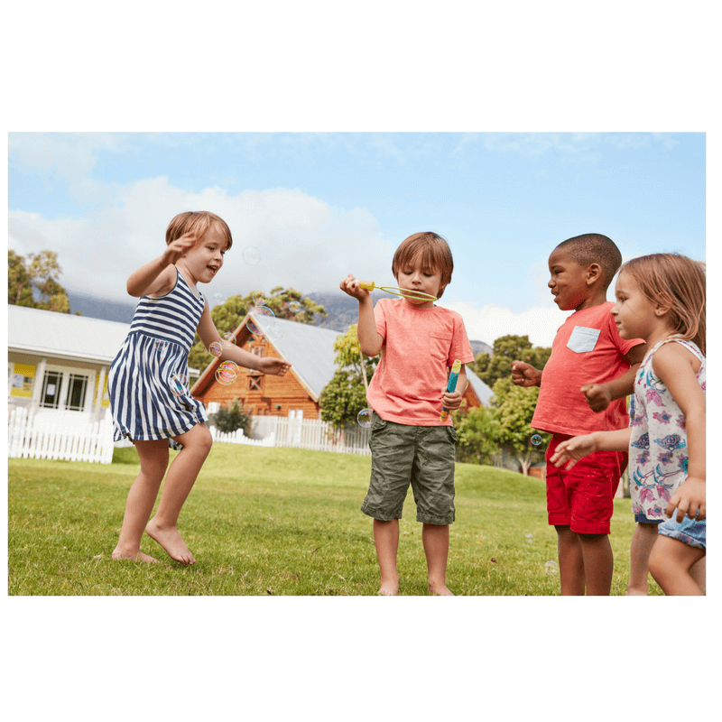 4 children playing together at park or school blowing bubbles