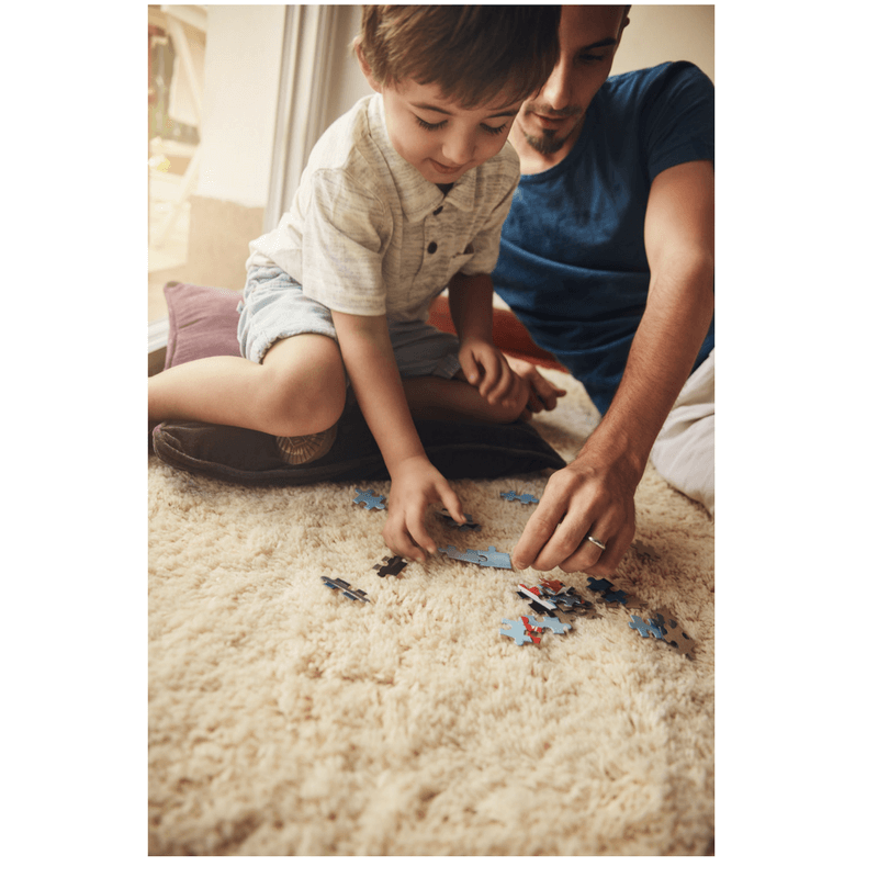 father and son sitting on the floor playing with cars