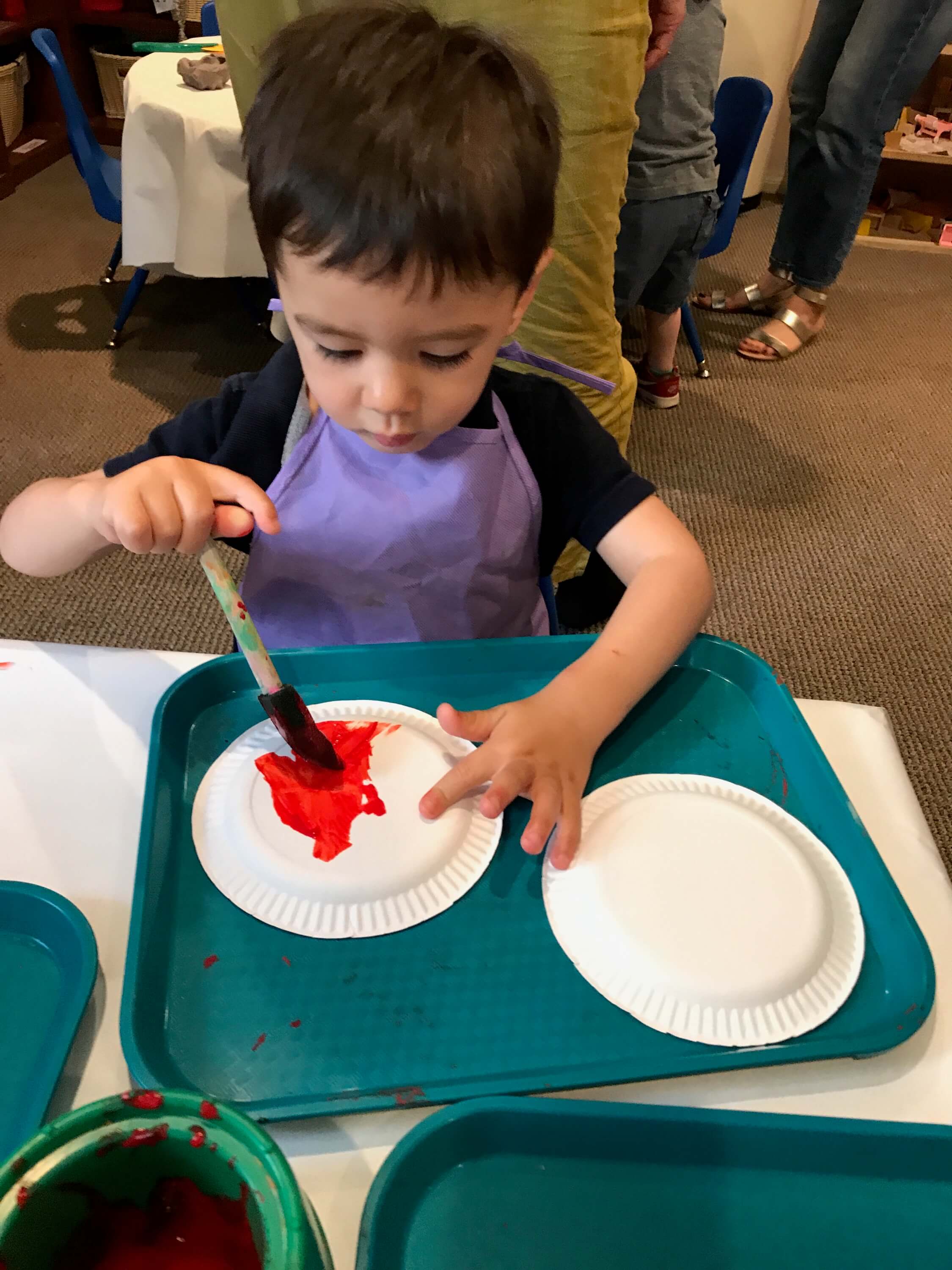 toddler paiting paper plate at early childhood development associates' class