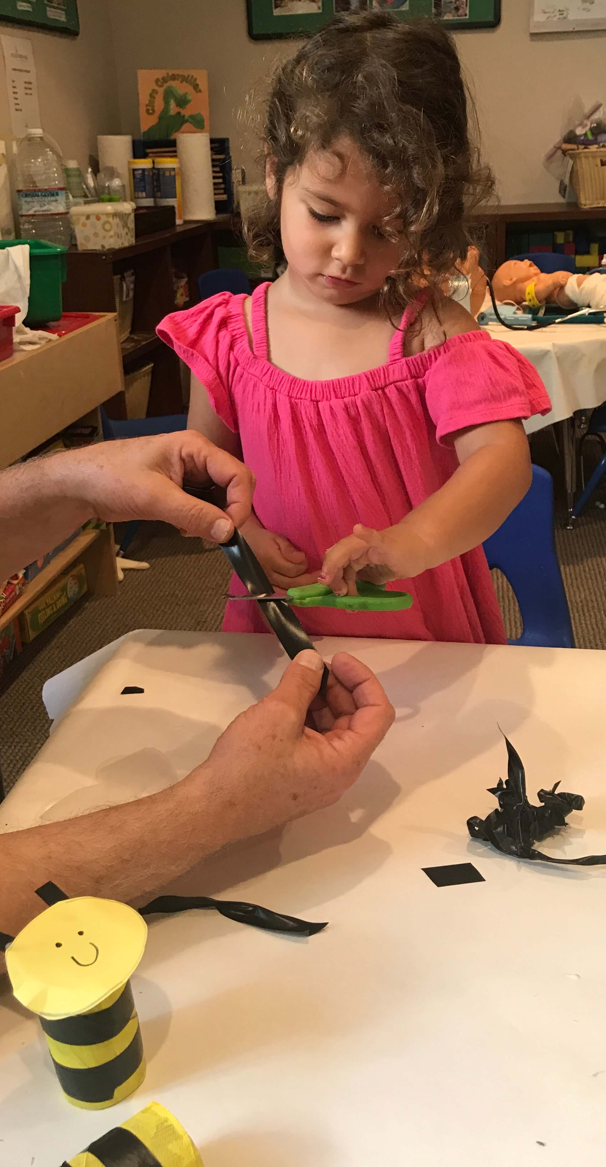 toddler learning to cut with scissors at early childhood development associates' class