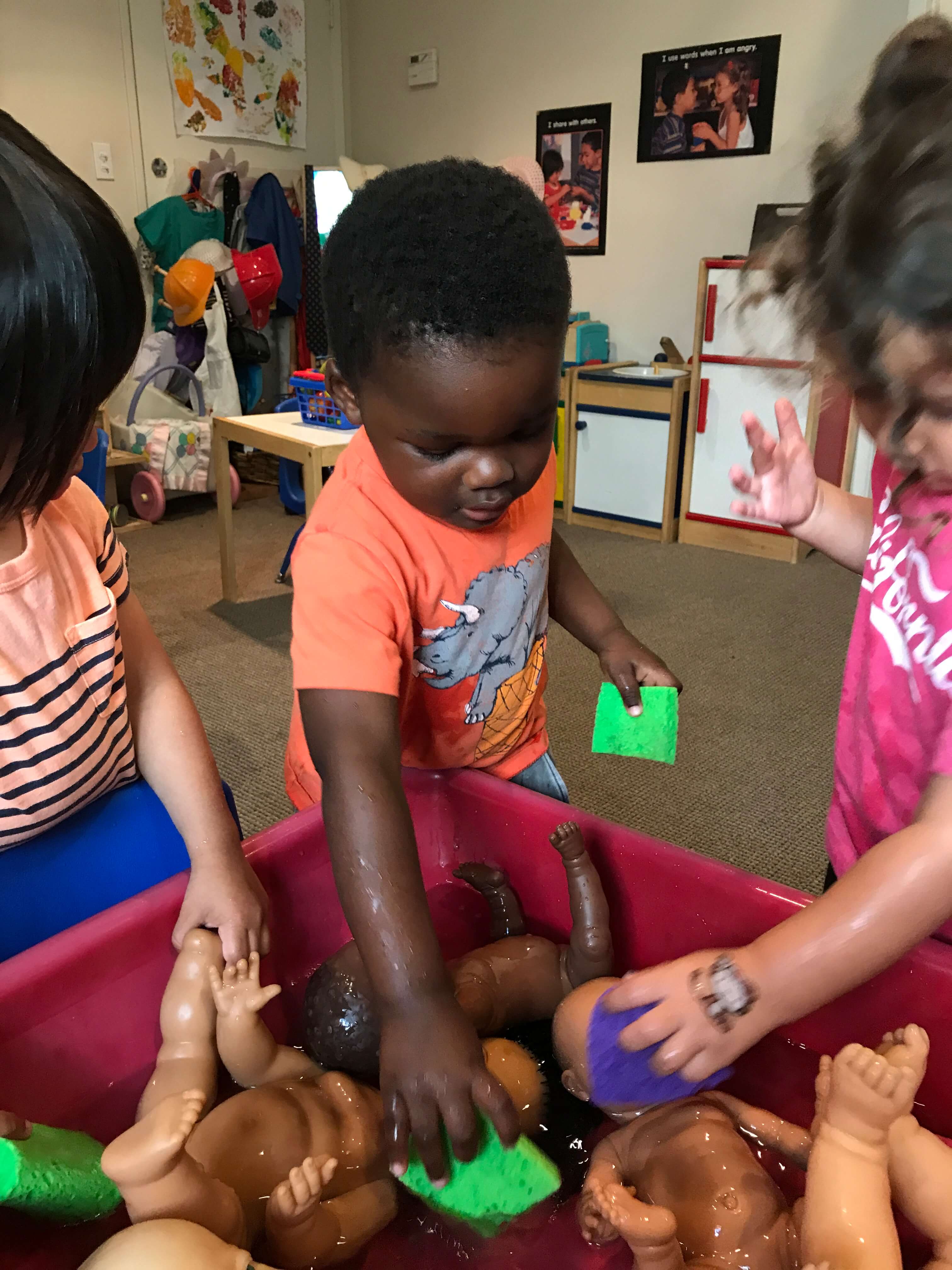 3 toddlers playing with water in sensory table at early childhood development associates