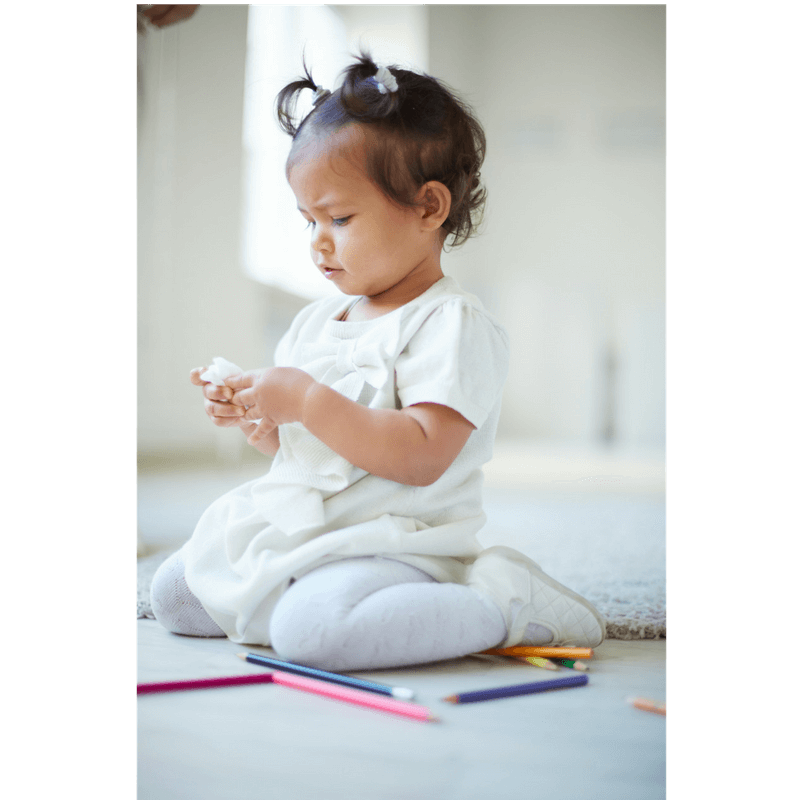 little girl playin on the floor with pencils and paper while waiting