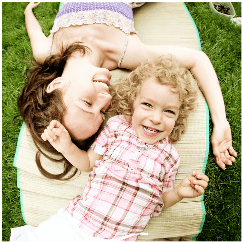 mother and daughter lying on the grass smiling