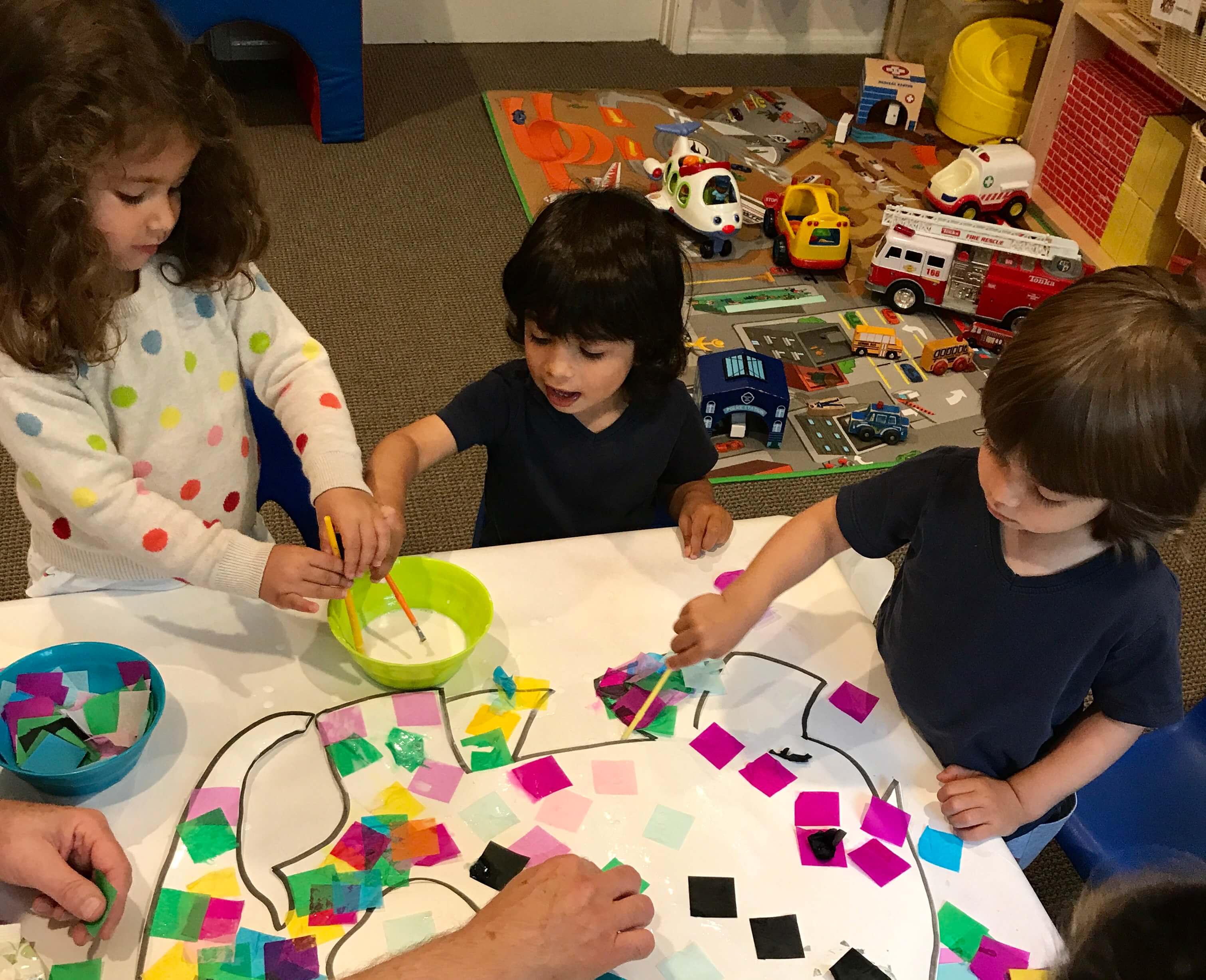 children gluing tissue paper in a picture of an Elefant at Early Childhood Development Associates' class