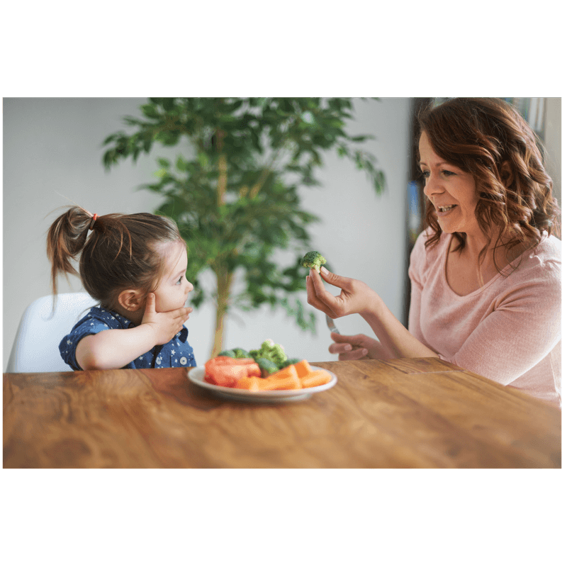 mom modeling how to eat healthy sharing a brocolli with toddler daughter