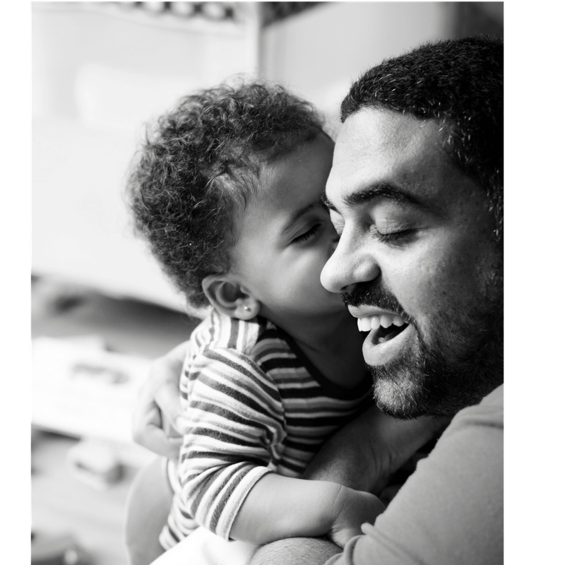 black and white picture: little boy giving his dad a kiss