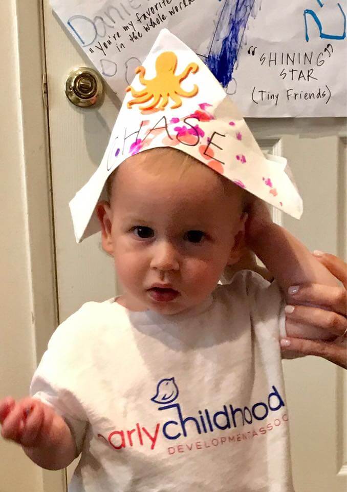 child wearing paper hat at Early Childhood Development Associates class