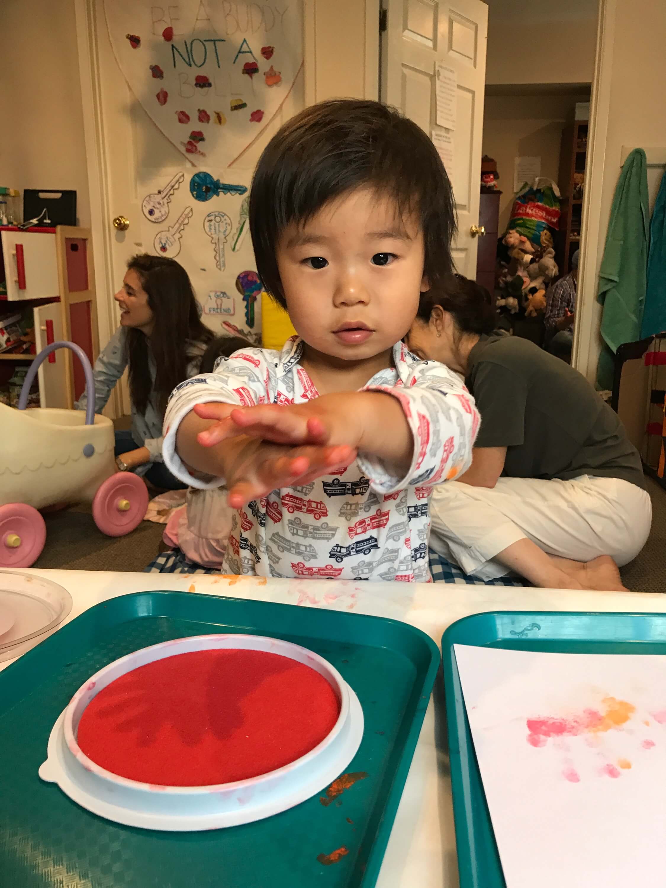 toddler making handprints with red paint at Early Childhood Development ASsociates' class
