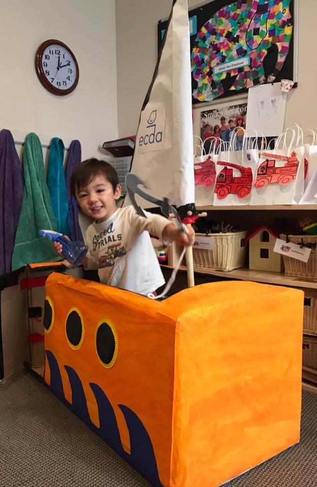 toddler playing in our big sail boat made from a cardboard box at Early Childhood Development ASsociates' class