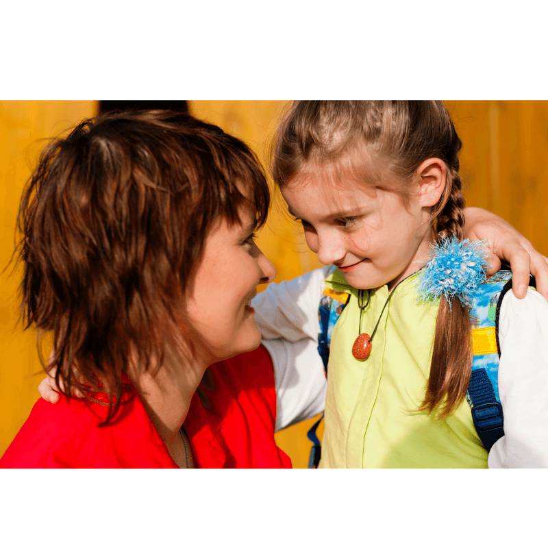 mother hugging daugher (daugher is wearing her backpack and ready to bo to school in the morning)