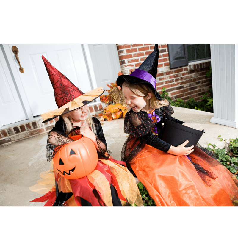 2 toddler girls wearing costumes looking happy after trick-or-treating