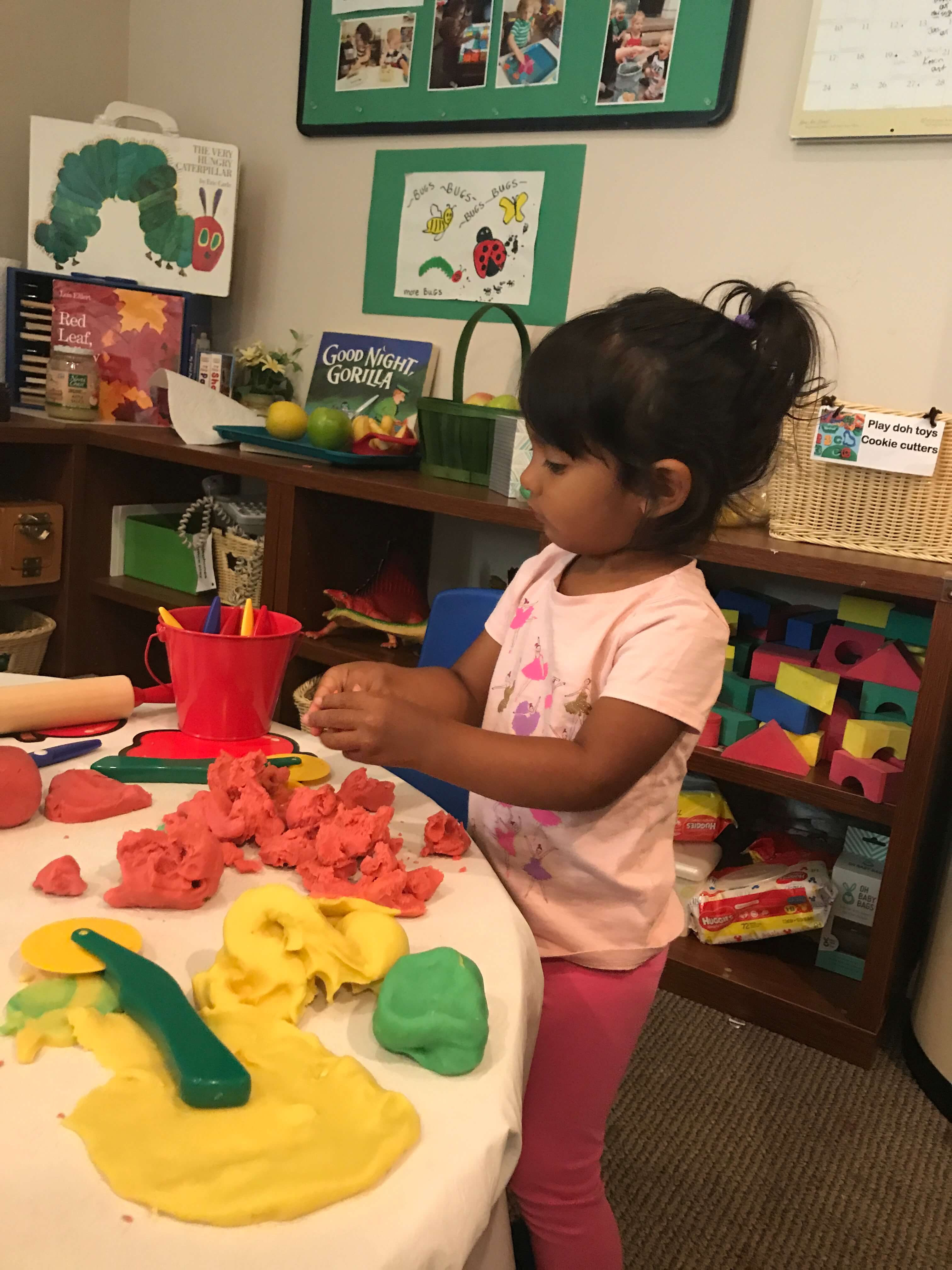 toddler girl playing wtih playdoh at early childhood development associates class