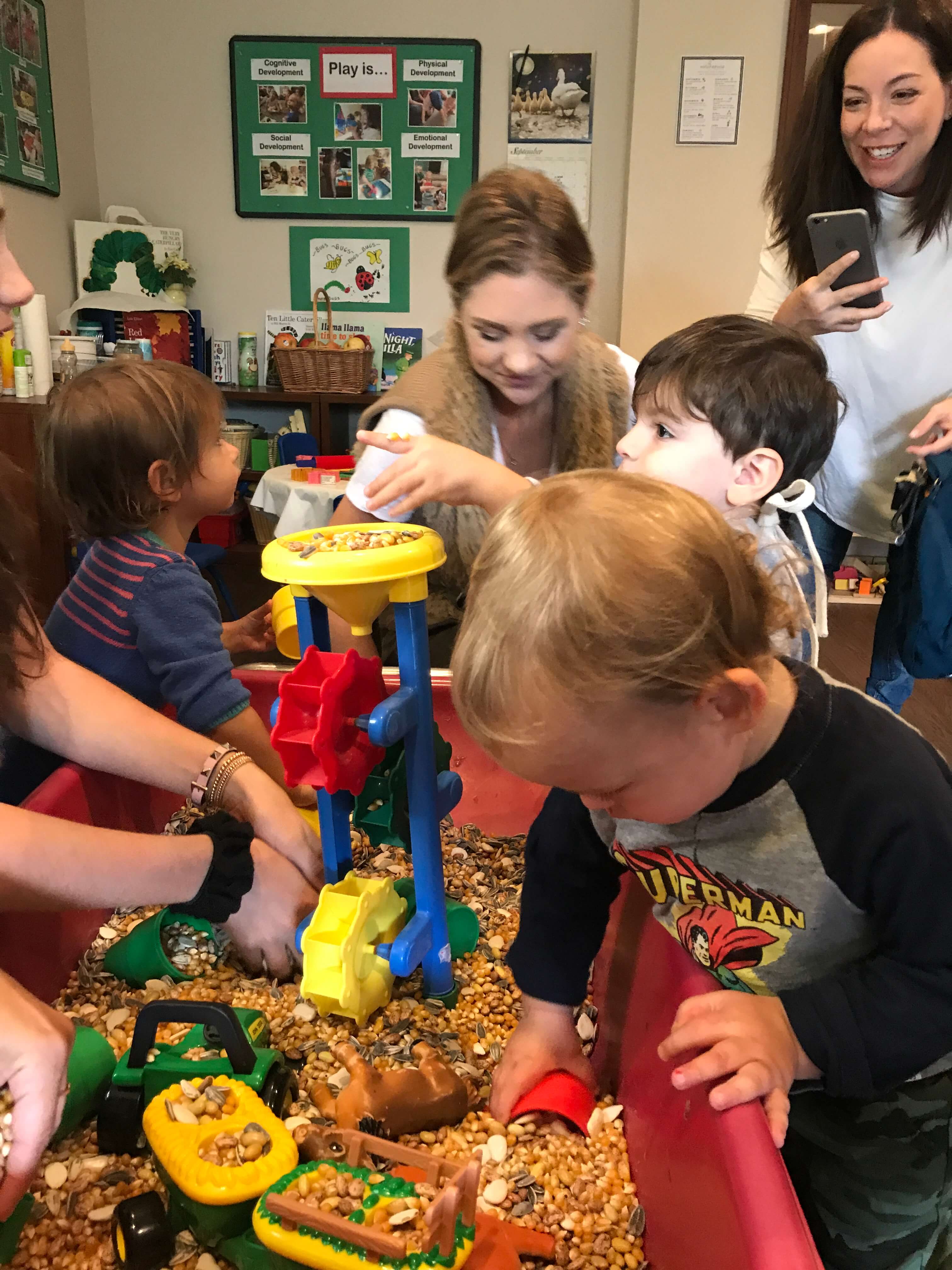 toddlers playing at sensory table with seeds at ecda