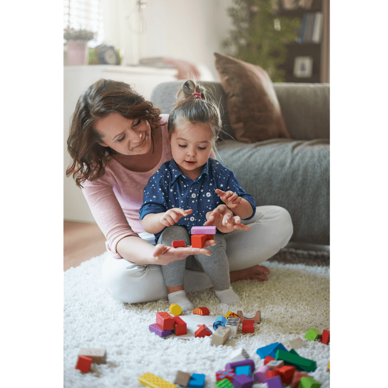 mother and toddler girl playing with woden blocks on the floor