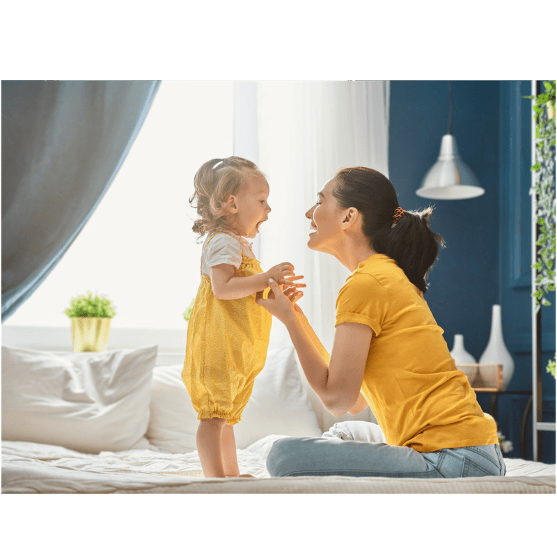 mother trying to help toddler daughter to stand byherself 